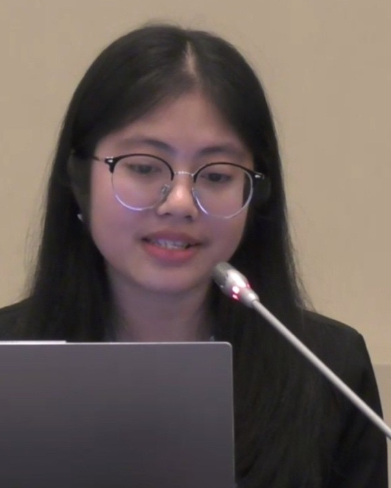 Thyda speaking at a microphone behind a laptop.